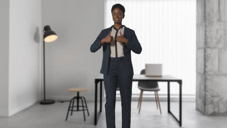 Portrait-Of-Smiling-Businesswoman-Wearing-Suit-Giving-Thumbs-Up-Gesture-Standing-In-Modern-Open-Plan-Office